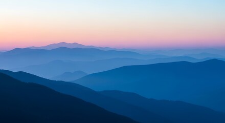 Fototapeta premium Blue mountain ranges fading into the distance beneath a soft pastel sky at dawn or dusk
