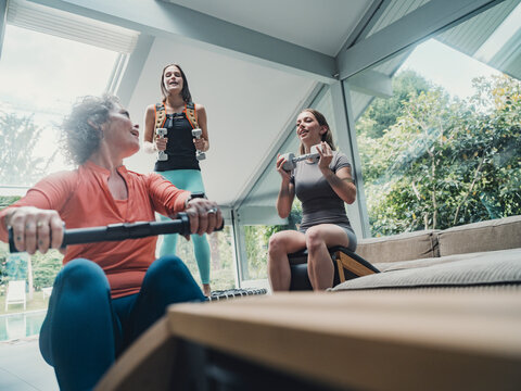 Family working out together at home with rowing machine and weights