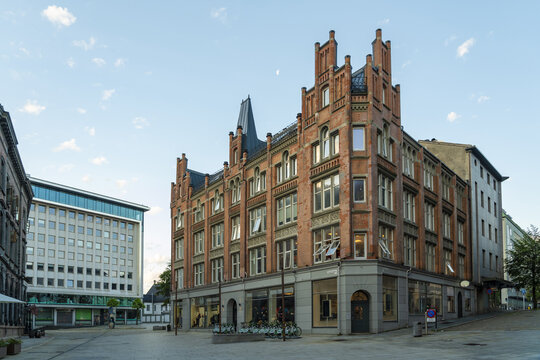 View of symmetrical brick building with stepped gables stands proudly on a city corner under a serene sky, Bergen, Vestland, Norway.