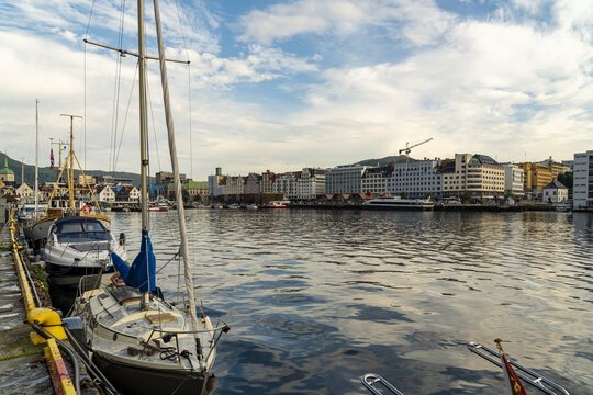 View of boats bobbing gently along the waterfront, reflecting the sky, with the city skyline in the background, Bergen, Vestland, Norway.