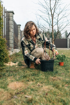 Person gardening outdoors in backyard wearing plaid jacket in spring
