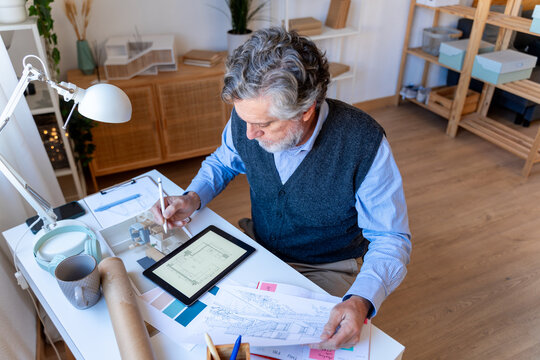 Architect drawing blueprints with tablet at modern workspace