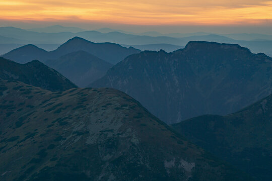 View of majestic, layered mountains fade into the distance under a warm, hazy sky, a ground photo capturing the serene beauty, Velka Kopa, Presov Region, Slovakia.