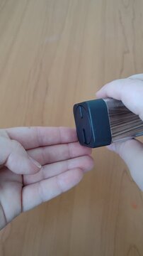 Close-up vertical video of hands pulling wooden toothpicks from a toothpick holder. Everyday kitchen accessory footage on wooden table, concept of dining, hygiene and food preparation.