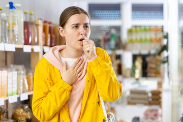 Woman in windbreaker coughing in store © caftor