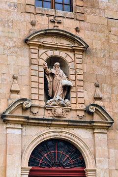 View of a saintly statue in a niche above an arched entrance, radiating history and reverence from the textured stone facade, Salamanca, Castile and Leon, Spain.