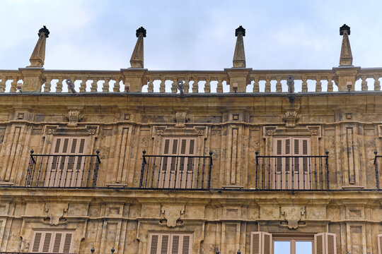 View of sandstone building with ornate balconies and elegant spires under a soft, overcast sky, Salamanca, Castile and Leon, Spain.