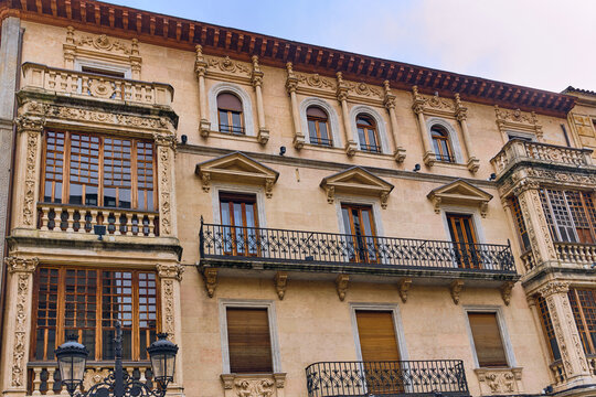 View of ornate balconies and windows adorn the historic facade, casting shadows on the stone, creating a timeless scene, Salamanca, Castile and Leon, Spain.