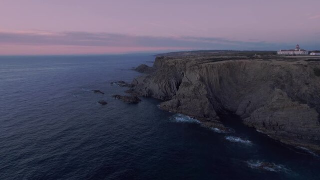 Atlantic coastal cliffs of Costa Vicentina with Farol do Cabo Sard&atilde;o lighthouse on the headland near Odemira in Alentejo Portugal inside Parque Natural do Sudoeste Alentejano e Costa Vicentina reveal