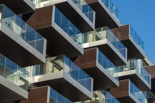 View of modern architecture featuring cantilevered balconies with glass railings reaching towards a clear blue sky, Oslo, Oslo, Norway.