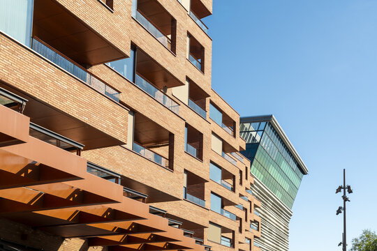 View of modern architecture featuring a brick building with glass balconies against a clear blue sky, Oslo, Oslo, Norway.