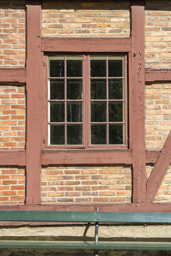 View of the window reflecting sunlight, framed by dark wood against a brick wall, casting shadows on a green bench, Oslo, Oslo, Norway.