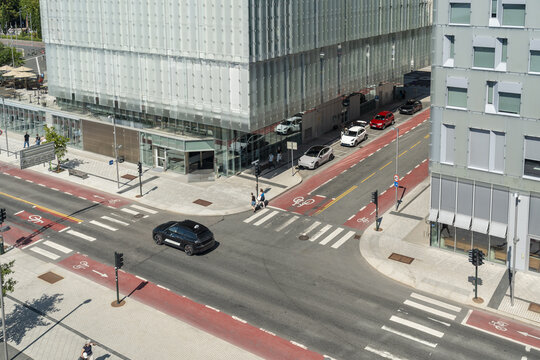 View of a modern cityscape where the stark angles of glass buildings meet the soft curves of passing cars and pedestrian walkways, Oslo, Norway.