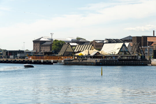 View of structures with distinct triangular roofs create a striking contrast against the calm water, reflecting the clear sky in Oslo, Norway.