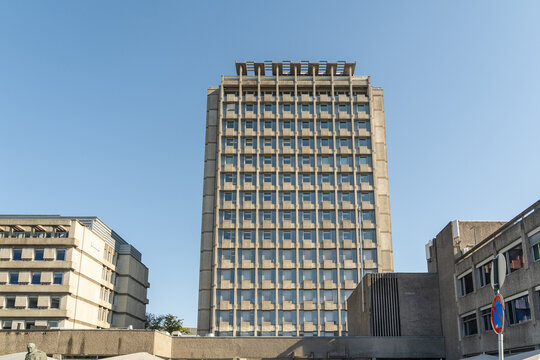 View of the towering concrete building rises against the clear blue sky, its repetitive window pattern creating a stark architectural statement, Oslo, Oslo, Norway.
