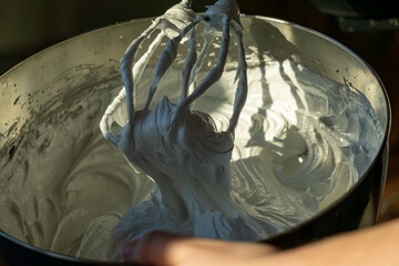 Fototapeta premium Whipped meringue mixture on mixer whisk in metal bowl