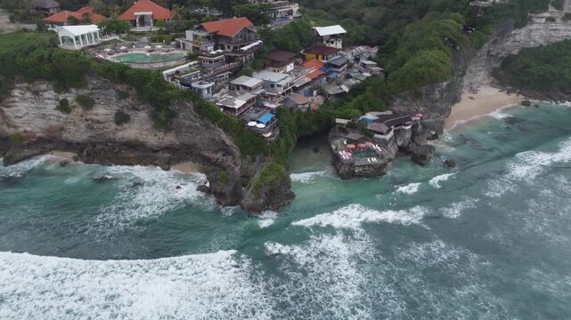 Aerial drone orbiting right around limestone cliff formation at Uluwatu Beach in Bali, Indonesia.