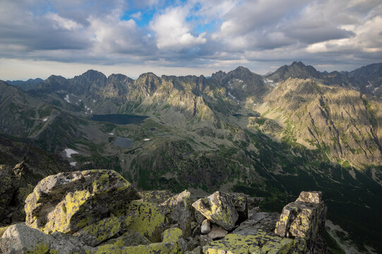 View of rugged peaks and serene lakes bask in the glow of sunlight, contrasting with shadows in the valley, Vysoke Tatry, Presovsky kraj, Slovakia.