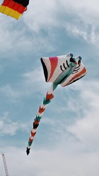 Single colorful kite flying high in sky during International Kite Festival on beach, Thailand. Seaside scene with tropical atmosphere, soft clouds, calm festival mood.