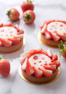 Closeup High-Angle Shot of Fresh Summer Strawberry Tarts Pie Pastry Setup on White Marble Table