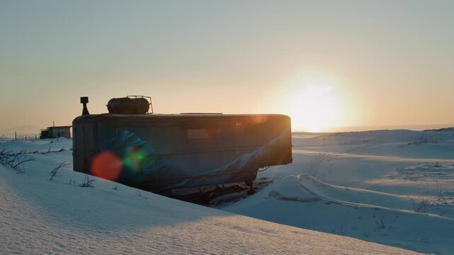 Tracked vehicle or RV camper parked in snow at sunrise