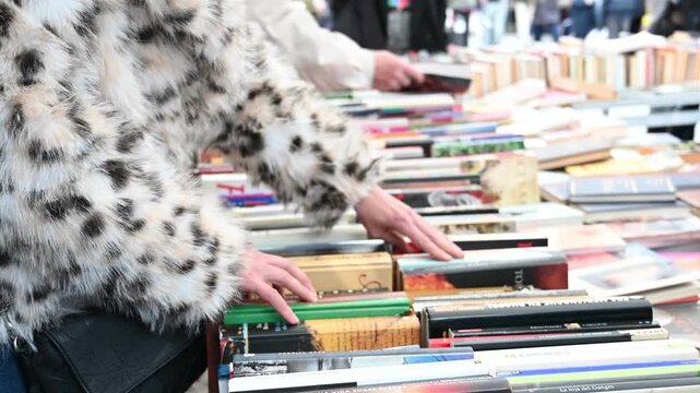 woman choose books at an outdoor flea market, 