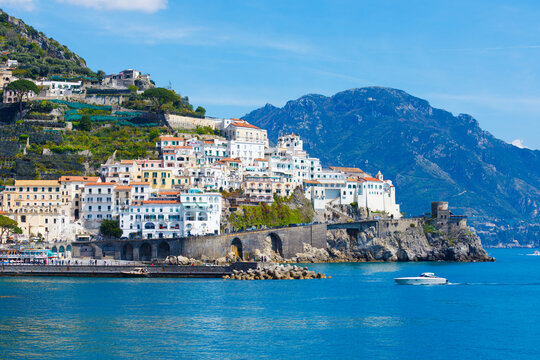 Picturesque view of Amalfi, Italy, with charming buildings perched on cliffside, overlooking blue waters of Mediterranean Sea. Amalfi coast is most popular travel and holiday destination in Europe