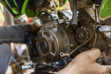 Obraz premium Focused mechanic performing motorcycle engine repair and maintenance in garage. close up of skilled person hand working on bike motor with precision and concentration