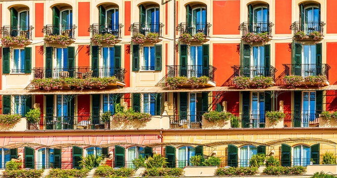 beautiful red and orange hotel facade of house with three green plants and braches and windows in retro italian european style