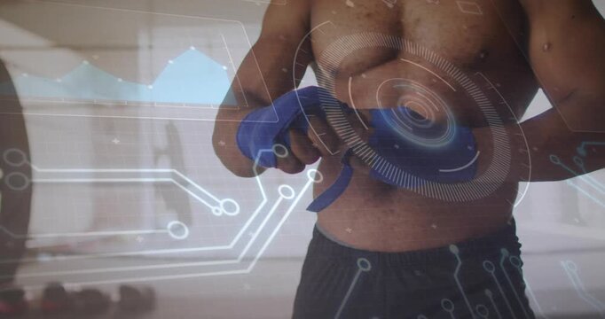 Gripping wrap taut, athlete wrapping blue hand wraps preparing for gym training HUD showing graphs