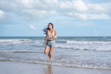 Fototapeta premium serene woman relaxing at seashore on summer vacation,running with carefree on sand beach