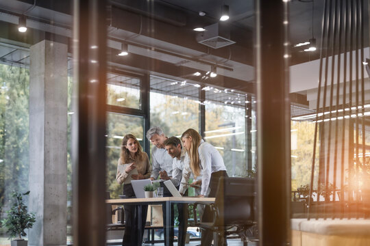 Creative business people, planning and meeting and brainstorming, ideas or strategy at office, view from glass wall