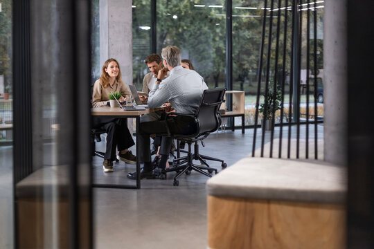 Creative business people, planning and meeting and brainstorming, ideas or strategy at office, view from glass wall