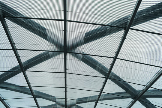 Modern architecture roof of glass and steel shows grid pattern and beams forming symmetry in structure for contemporary canopy design