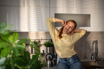 Woman stretching in kitchen enjoying morning sunlight and relaxation