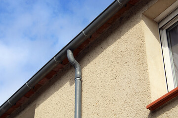 Gouttière zinc gris sur la façade de la maison, descentes rondes sur la façade en crépis © CURIOS