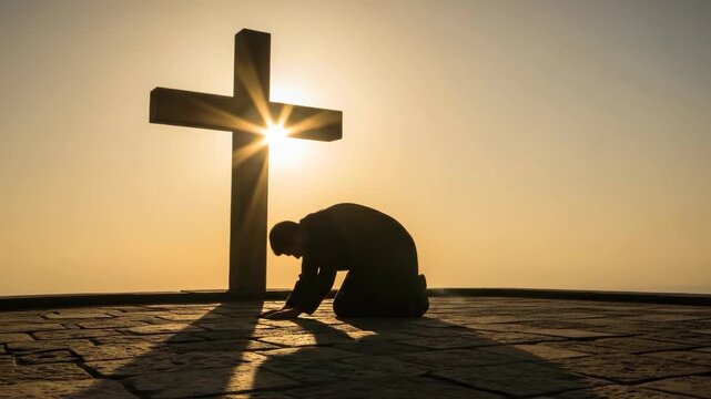 Man kneeling and praying before a cross at sunset. Faithful believer bowing down near a crucifix. Spiritual devotion and christian worship at golden hour light.