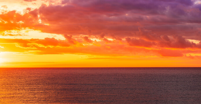 Dramatic seascape of sunset or sunrise sky with clouds during morning or evening. Dramatic sunset over the sea with orange clouds and sun above ocean water