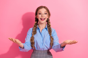 Excited young student with long braids and glasses gesturing on pink background showcasing joyful...