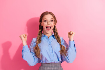 Smiling young student with braids expressing excitement and positivity against pink background...