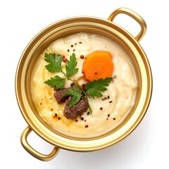Top-down view of creamy soup in a gold pot, garnished with meat, carrot, and parsley, on a white background