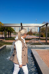 Obraz premium Elegant woman enjoys a sunny day by the fountain in a vibrant 50's inspired lifestyle