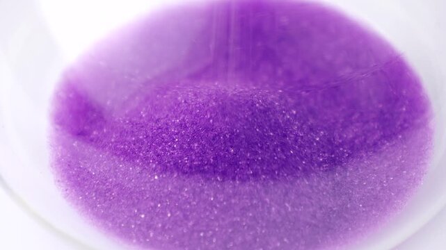 Transparent hourglass with flowing purple sand on white background. Old classic timer. Time concept