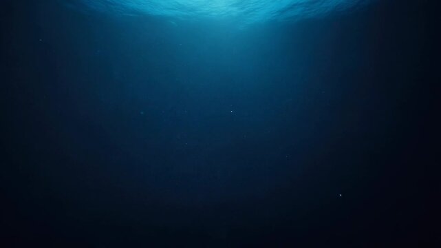 Abstract underwater scene depicting deep blue water with subtle light rays filtering from the surface and tiny floating particles. Conveys depth, tranquility, and mystery, ideal for marine, science