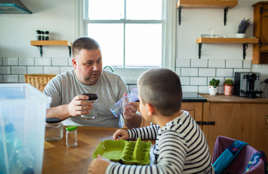 Father teaching son about recycling in home kitchen