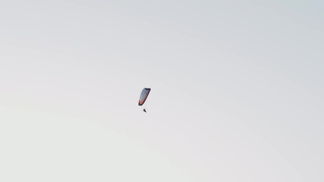 Vertical paraglider canopy carrying paramotor pilot gliding across soft gradient sky with wide open space. Powered paragliding adventure continuing smooth aerial motion extreme outdoor lifestyle
