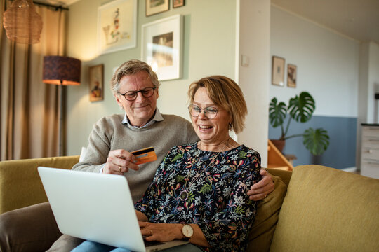 Smiling senior couple shopping online at home
