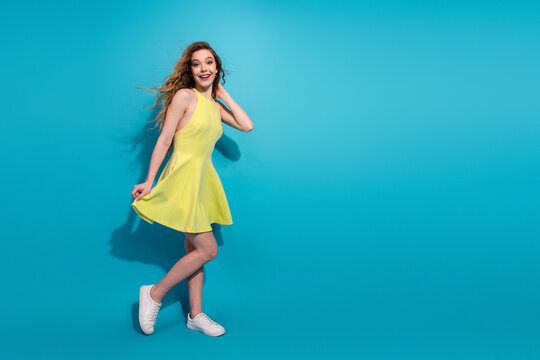Stylish young woman in a yellow dress on vibrant blue background modeling for lifestyle and fashion imagery