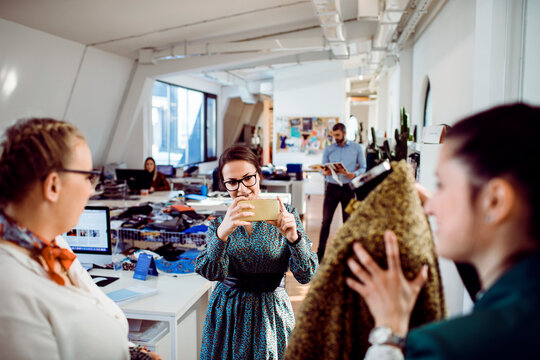 Fashion design team photographing fabric in modern office
