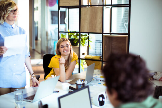 Coworkers brainstorming with laptops in modern office